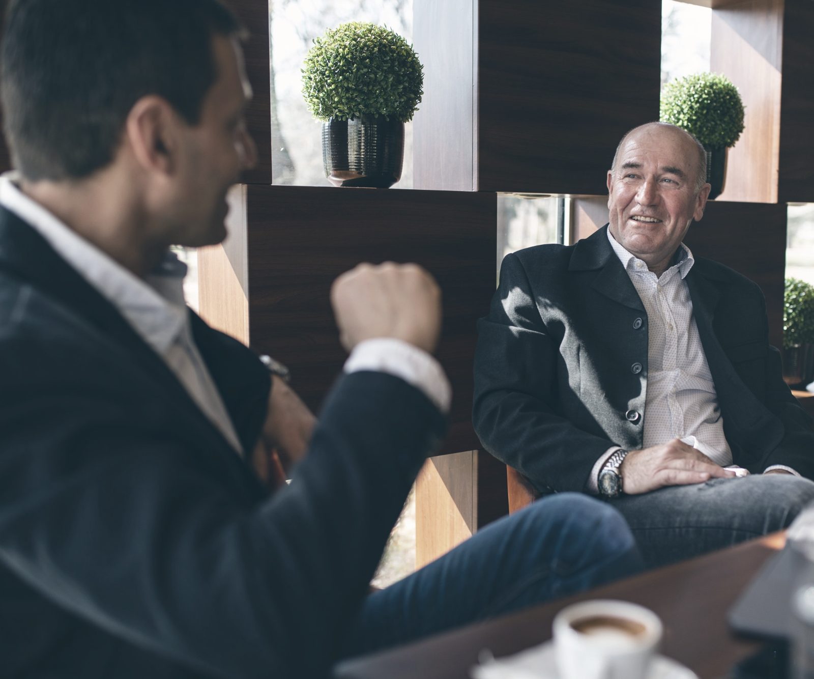 One businessman animatedly describing an opportunity to another, who listens and smiles