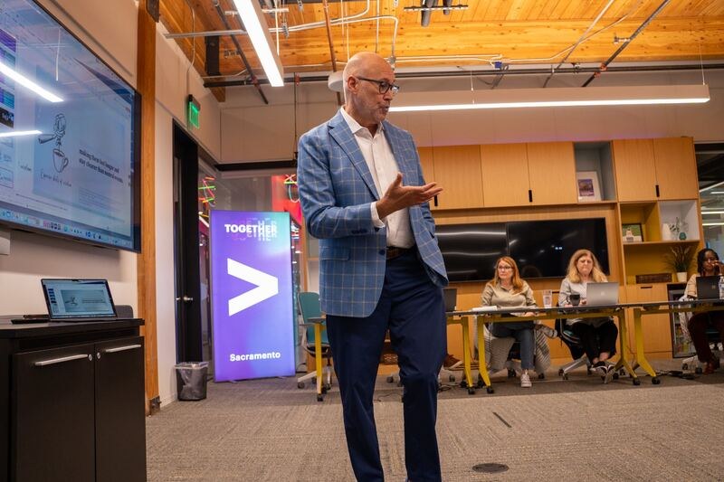 Jon Newsome coaching a room of professionals, with an Accenture banner behind him